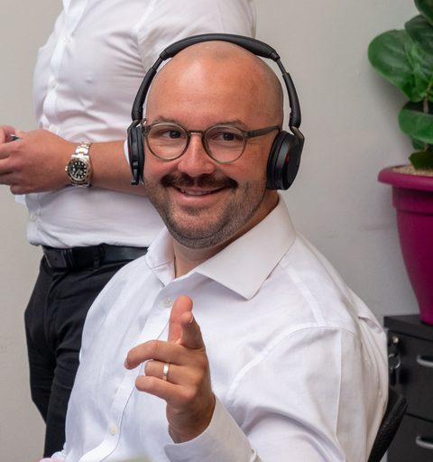 Alex W of Aspire Estates at his desk, pointing to camera